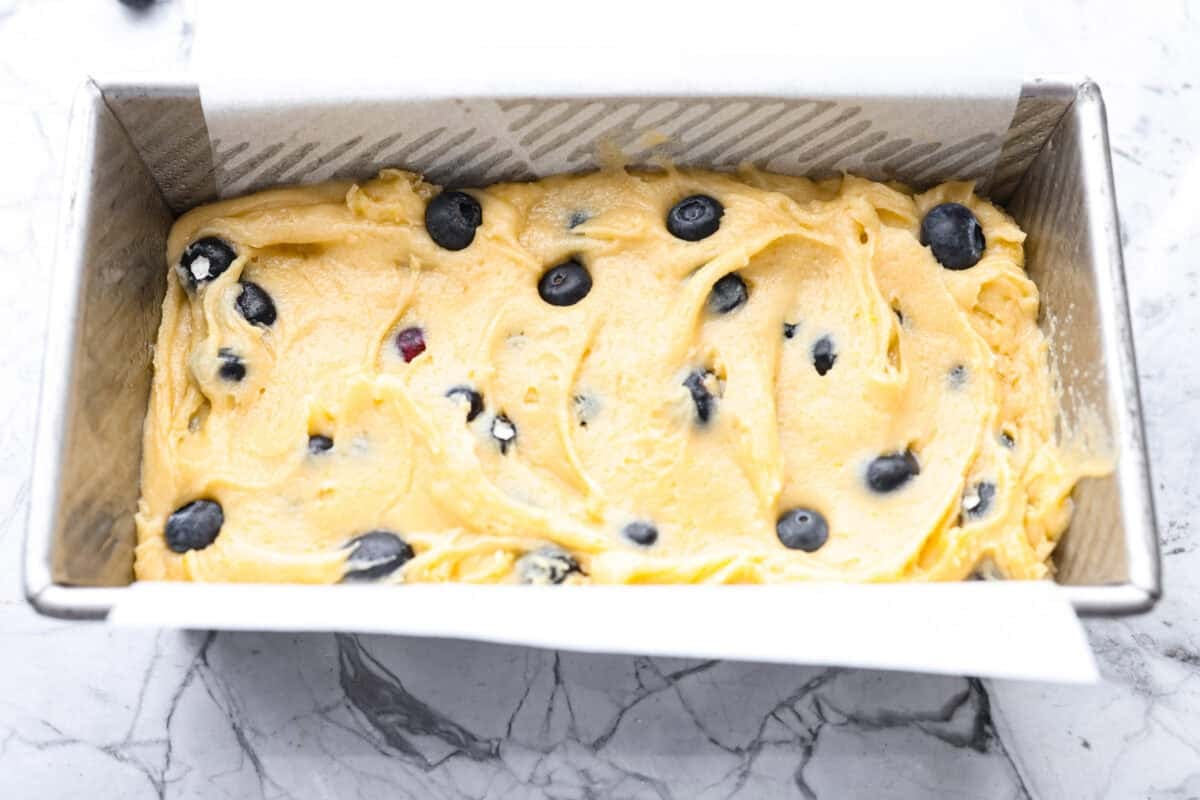 This 5 Ingredient Blueberry Bread is the little shortcut loaf you’ll make once and then suddenly need every weekend. It’s soft, sweet, full of juicy blueberries, and comes together with only five simple ingredients. 5 ingredient blueberry bread batter added to a loaf pan.