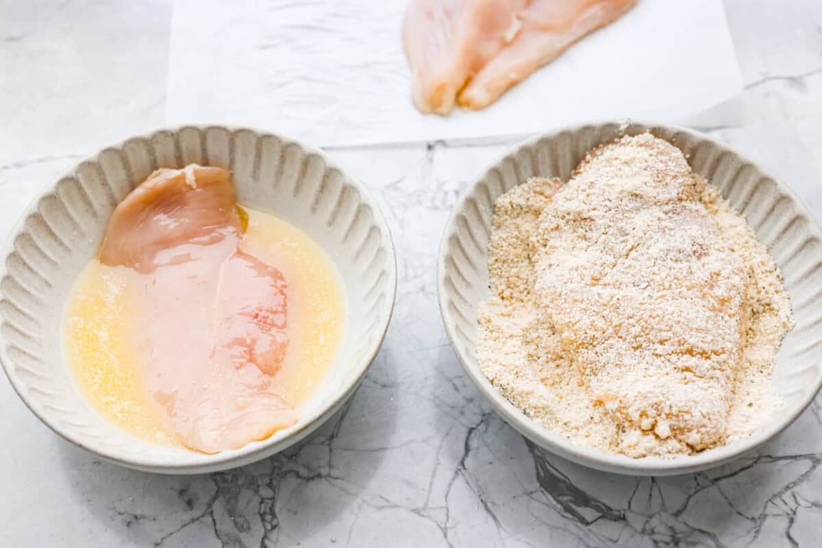 My family and I cannot get enough of this versatile summer vegetable! Whether you use it for a side dish or the entrée, its tender texture and ability to absorb flavor is unmatched. Take advantage of zucchini being in season and try out some of my other favorite zucchini recipes! Chicken being dredged in egg wash and bread crumbs in separate bowls.