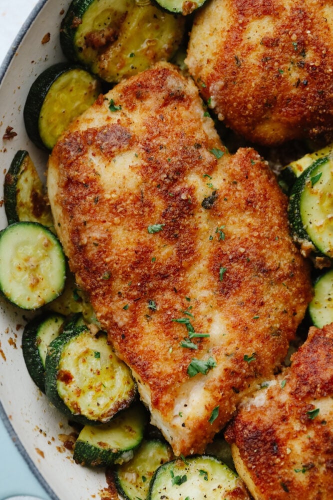 My family and I cannot get enough of this versatile summer vegetable! Whether you use it for a side dish or the entrée, its tender texture and ability to absorb flavor is unmatched. Take advantage of zucchini being in season and try out some of my other favorite zucchini recipes! Close-up of crispy parmesan garlic chicken with zucchini.