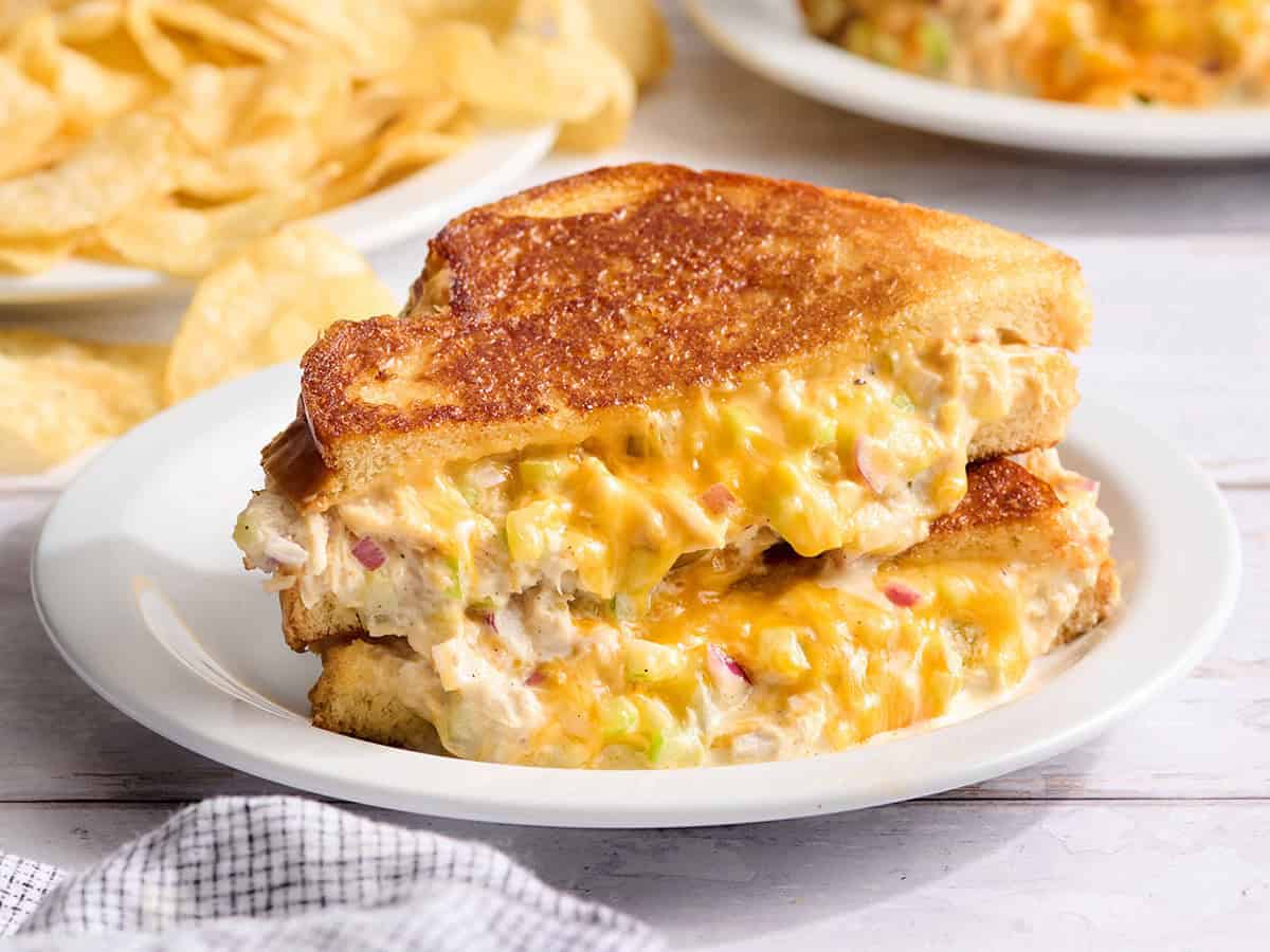 Tuna melt sandwich cut in half on a white plate.