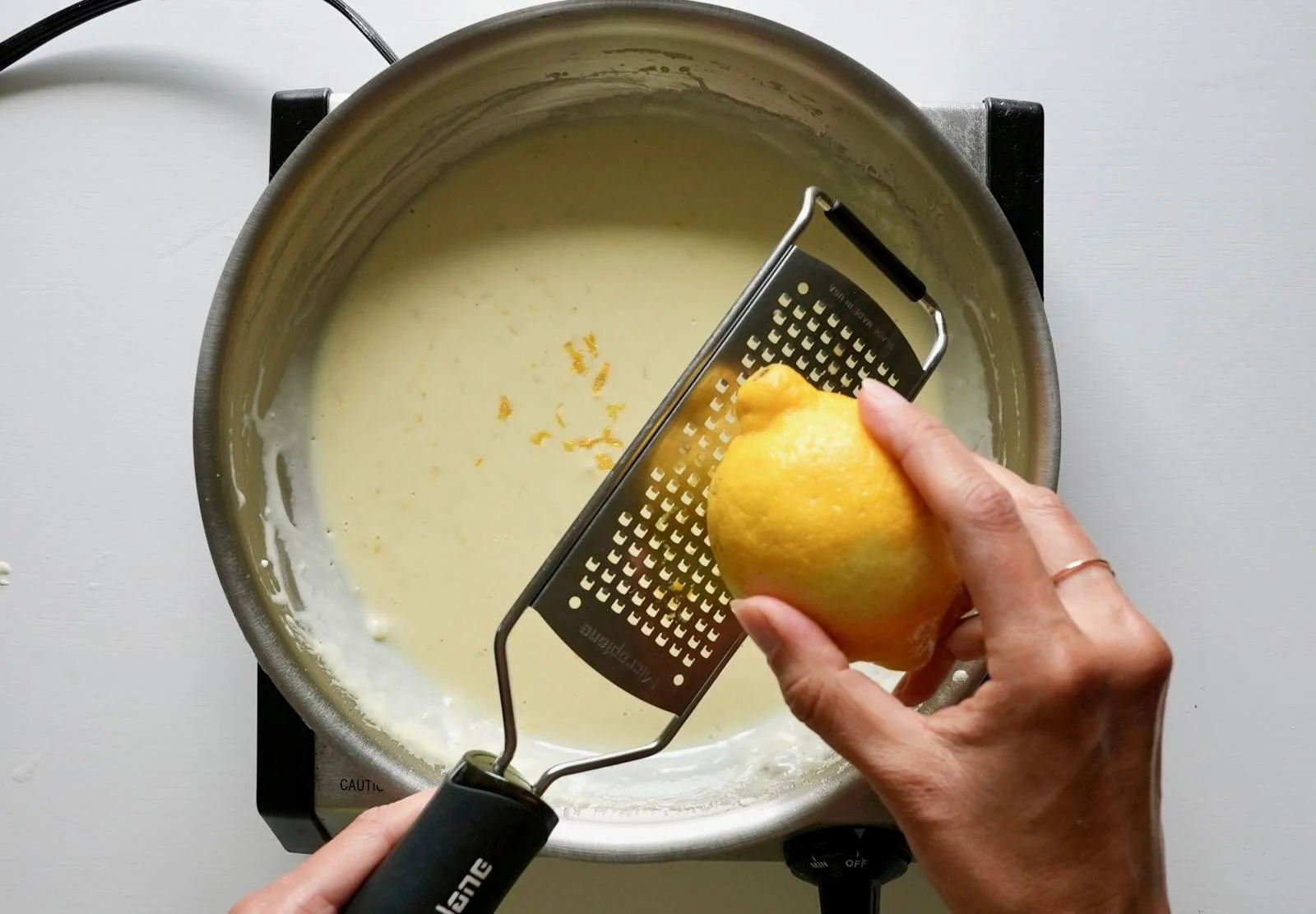 Zesting lemon into sauce.