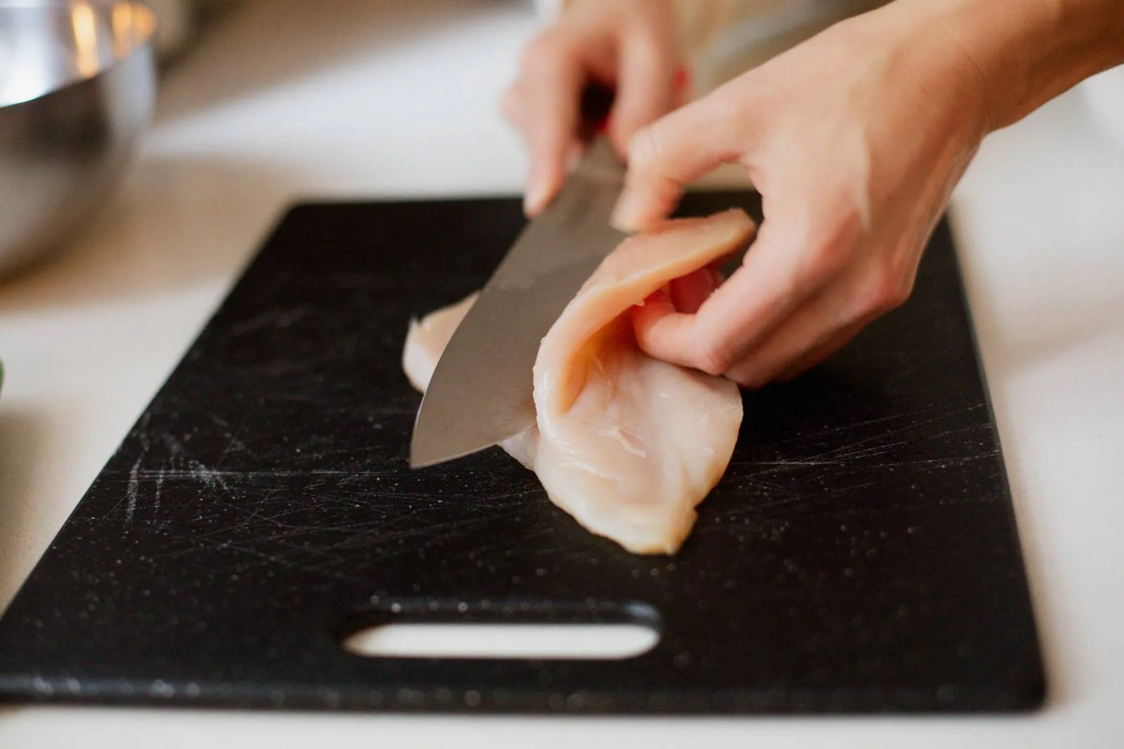 Slicing chicken in half lengthwise.