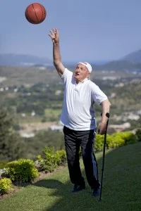 Old man shooting a basketball ball and looking to sky in the park