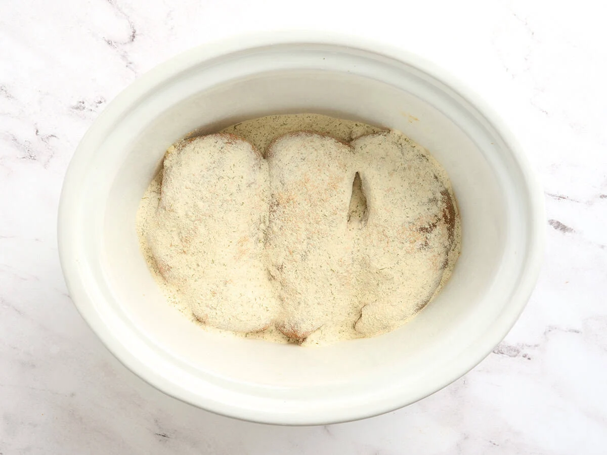 Chicken breasts in a crockpot with seasonings.