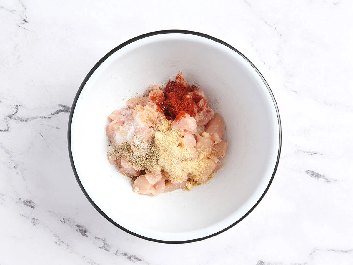 Chopped chicken tenders in a mixing bowl with seasonings.
