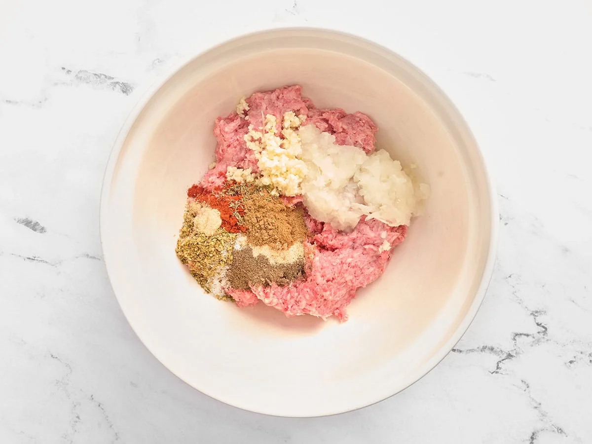 Ground beef, minced onion, seasonings, and minced garlic in a mixing bowl.