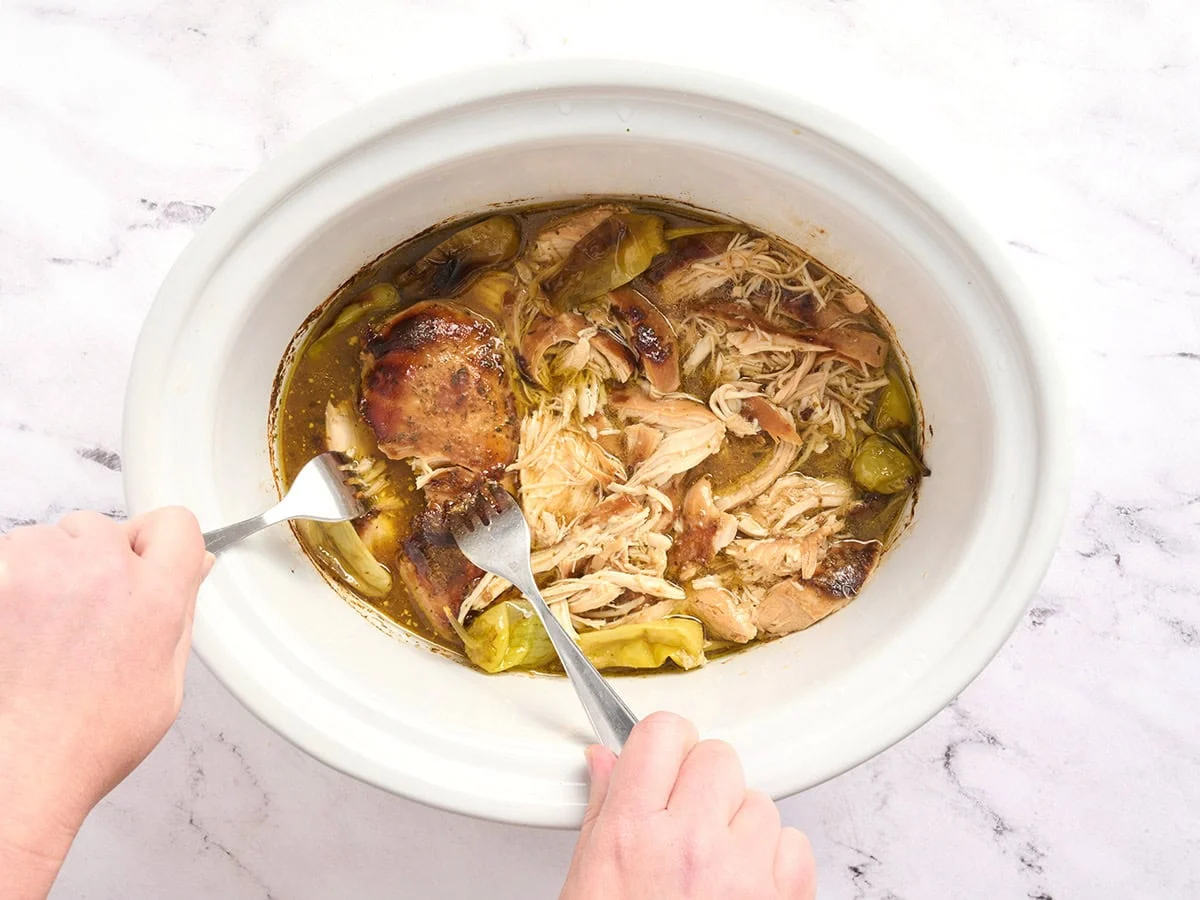 Forks shredded Mississippi chicken in a crockpot.