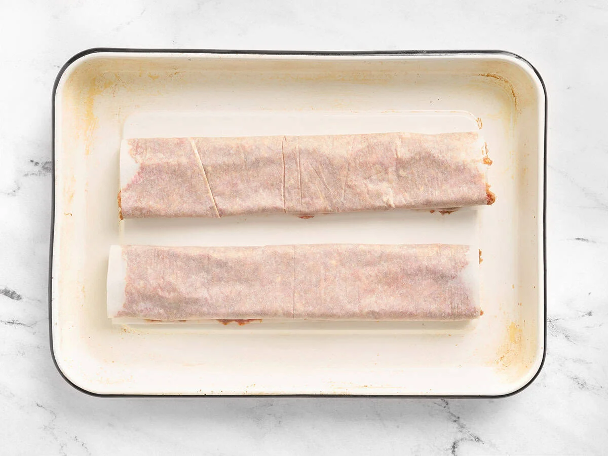 Meat rolled in parchment on a sheet pan.