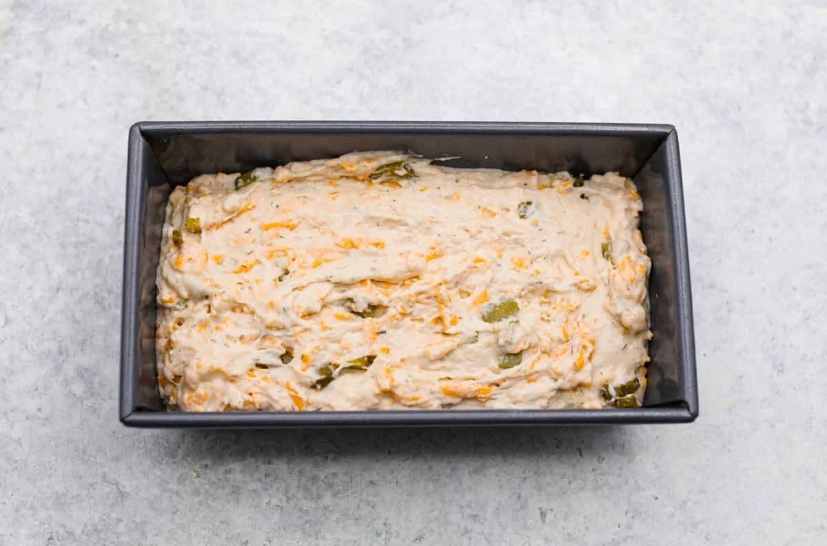 Dill pickle bread dough added to a loaf pan. 