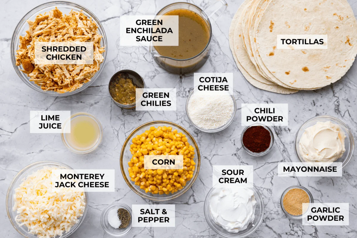 These street corn chicken enchiladas are creamy, cheesy, and packed with zesty flavor. An easy 40-minute dinner the whole family will love. Overhead shot of labeled ingredients.