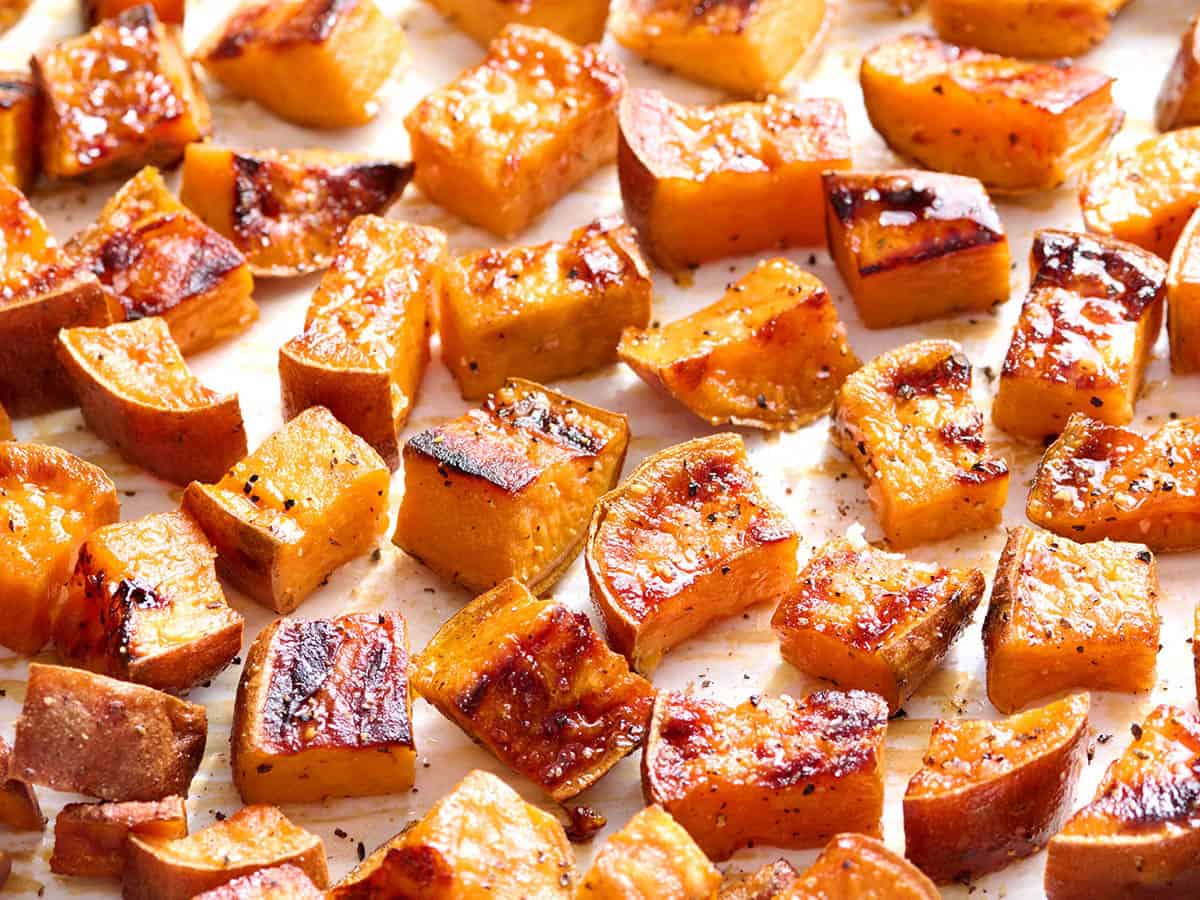 Front macro view of roasted sweet potato cubes on a sheet pan.