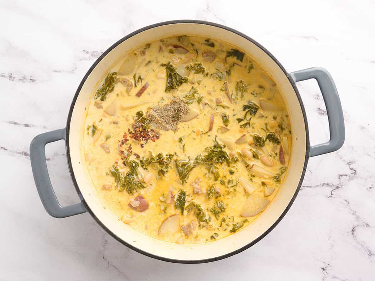 Black pepper and crushed red pepper added to a pot of zuppa toscana.