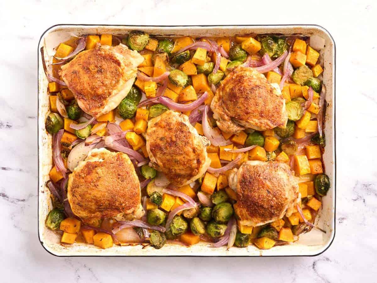 Overhead view of baked sheet pan chicken thighs and veggies.
