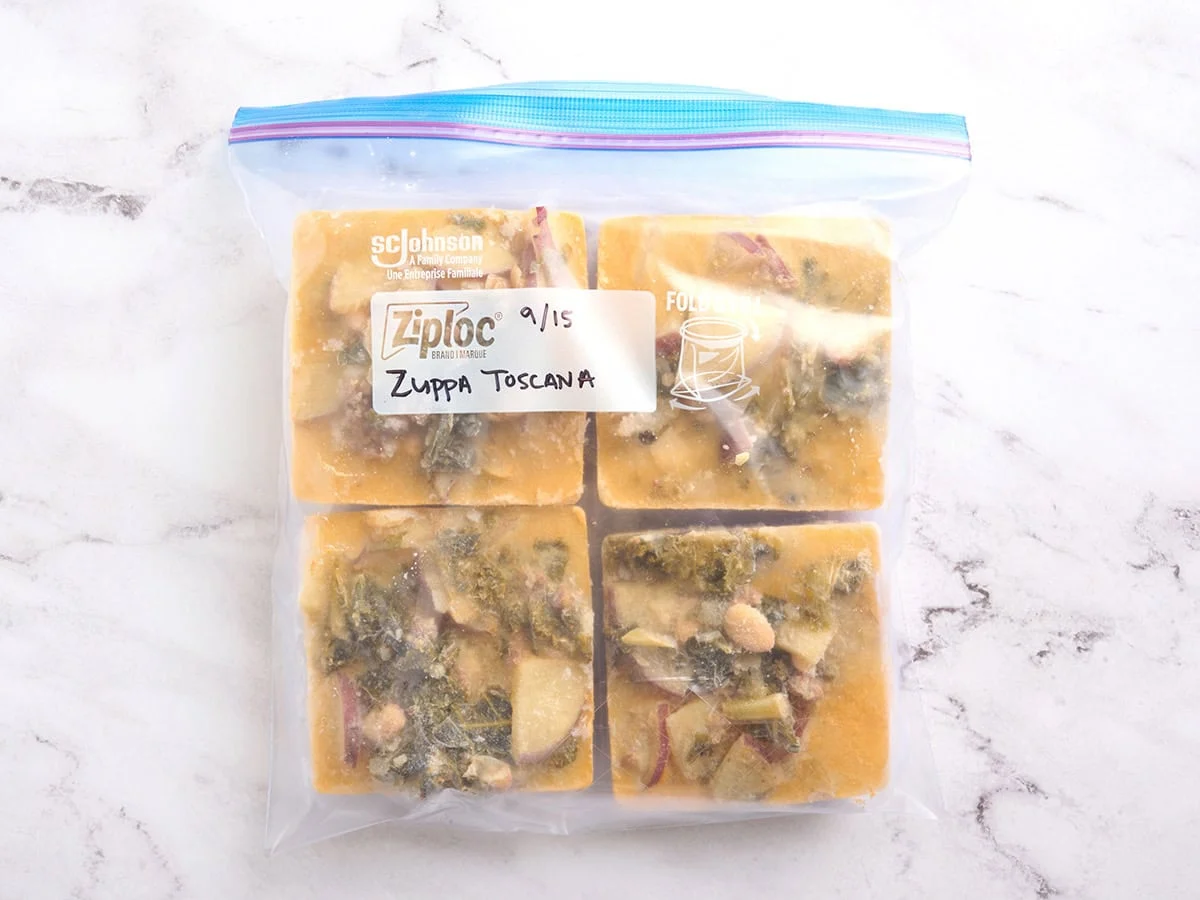 Overhead view of frozen cubes of zuppa toscana in a ziplock bag.