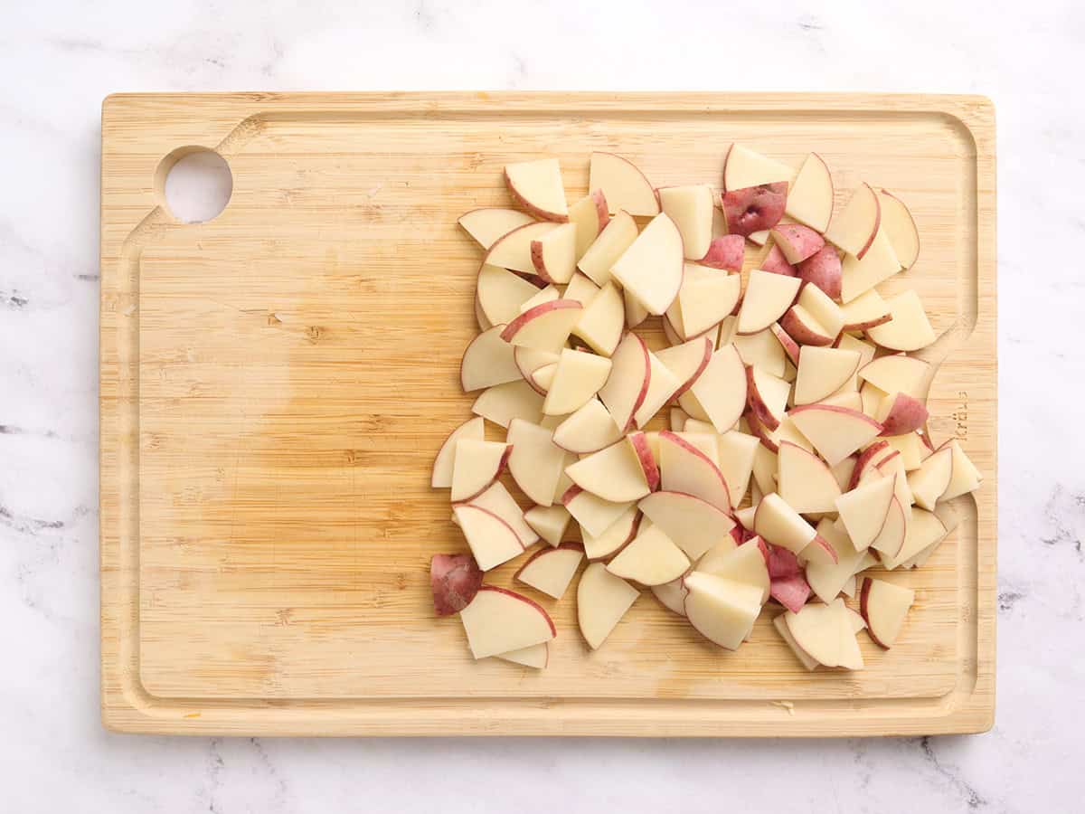 Sliced potatoes on a wooden cutting board.