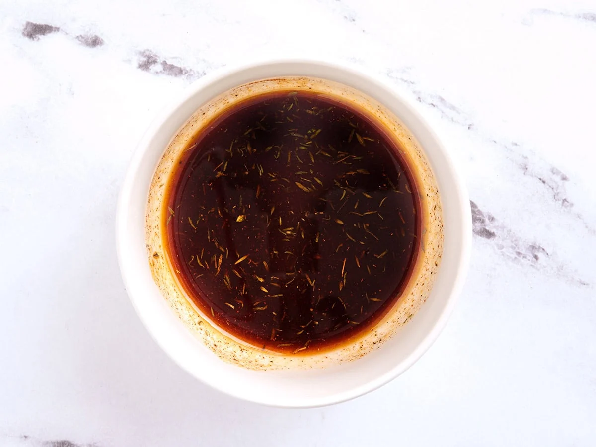 A seasoned oil mixture in a bowl for chicken thighs.