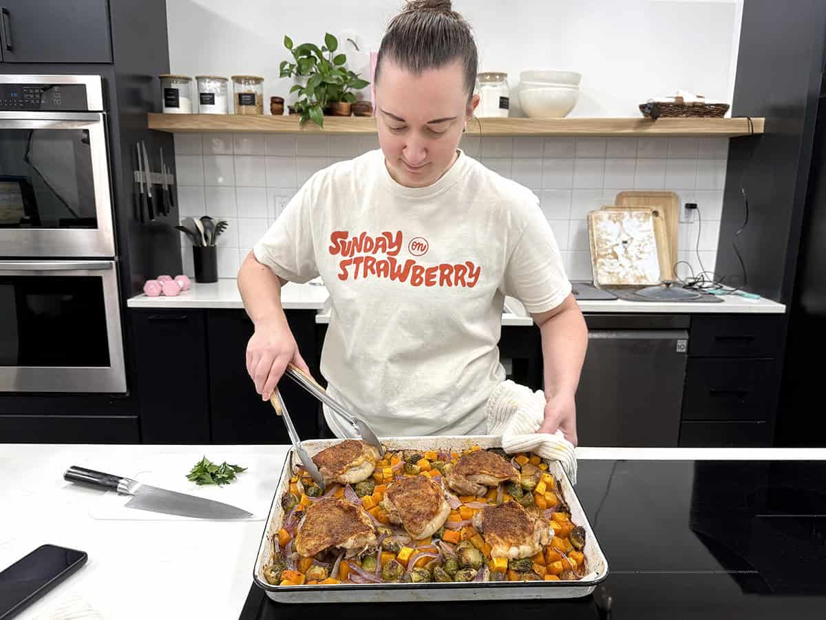 A women prepping sheet pan chicken thighs in a kitchen.