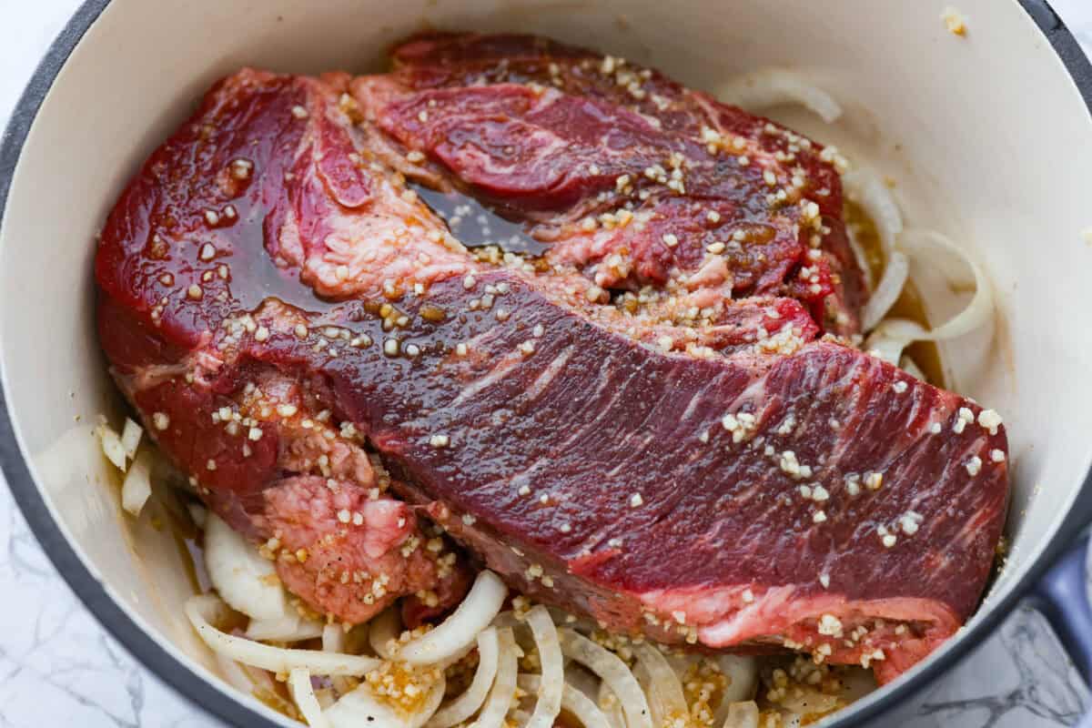 Chuck roast, onions, garlic and sauce added to the dutch oven. 