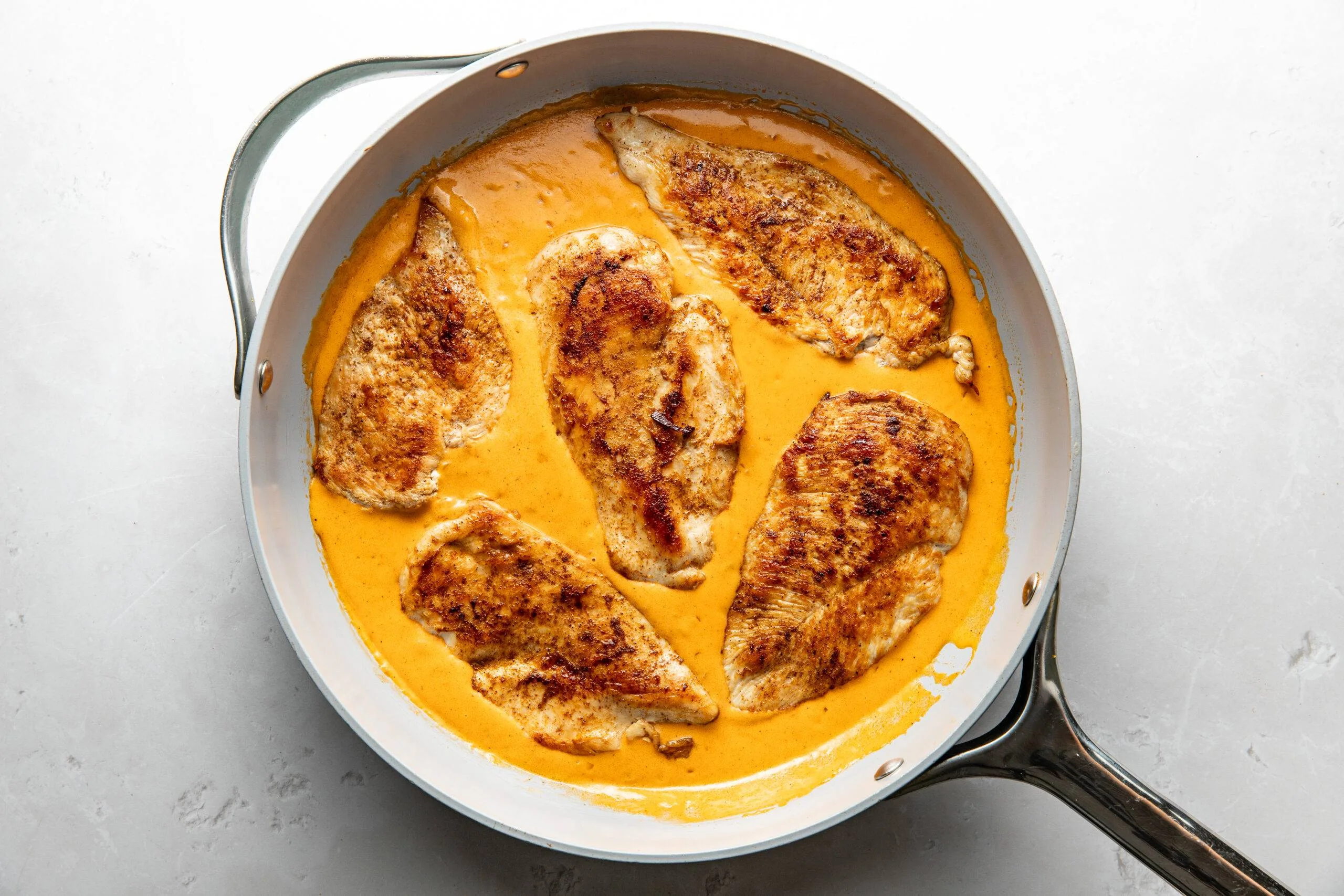Chicken in creamy cajun sauce in a skillet.