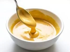 Honey Mustard Sauce dripping off a spoon into a bowl