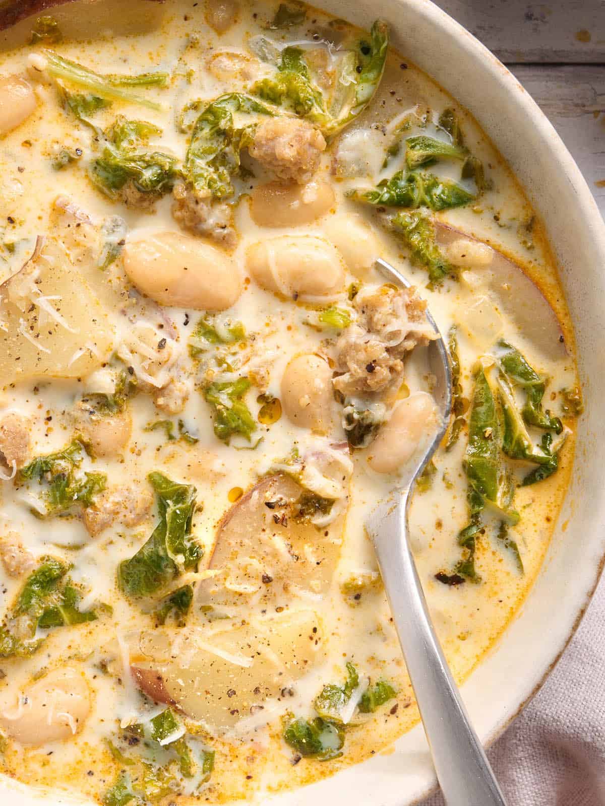 Overhead close up view of a bowl of zuppa toscana with a spoon.