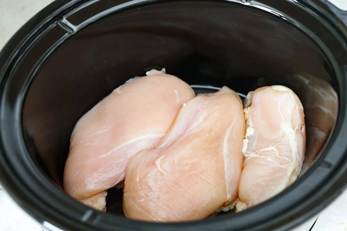 Crockpot creamy chicken pasta is the kind of dinner I need on a busy weeknight! Tender chicken cooks all day in a creamy marinara sauce, then you stir in pasta and cheese for the easiest comfort food dinner. Chicken breasts added to the bottom of the crockpot.