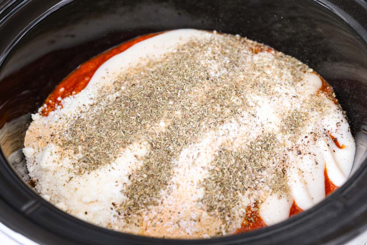 Crockpot creamy chicken pasta is the kind of dinner I need on a busy weeknight! Tender chicken cooks all day in a creamy marinara sauce, then you stir in pasta and cheese for the easiest comfort food dinner. Sauces and seasonings added to the chicken in the crockpot.