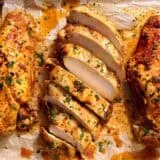 Overhead view of baked chicken breasts with one cut into slices.
