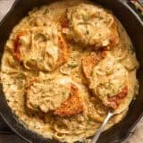 Overhead view of smothered pork chops in a skillet.