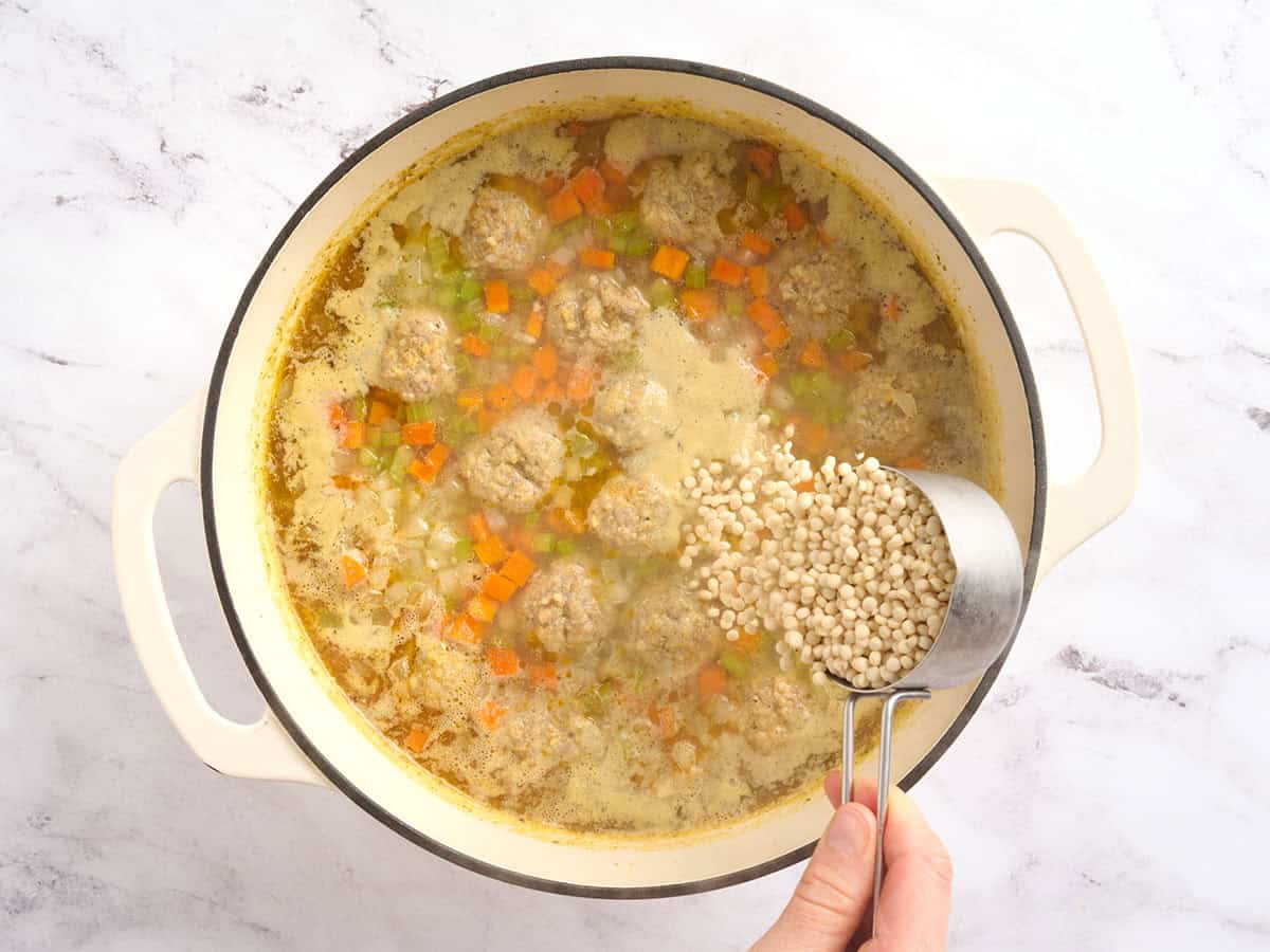 Pearl cous cous added to a pot of soup.