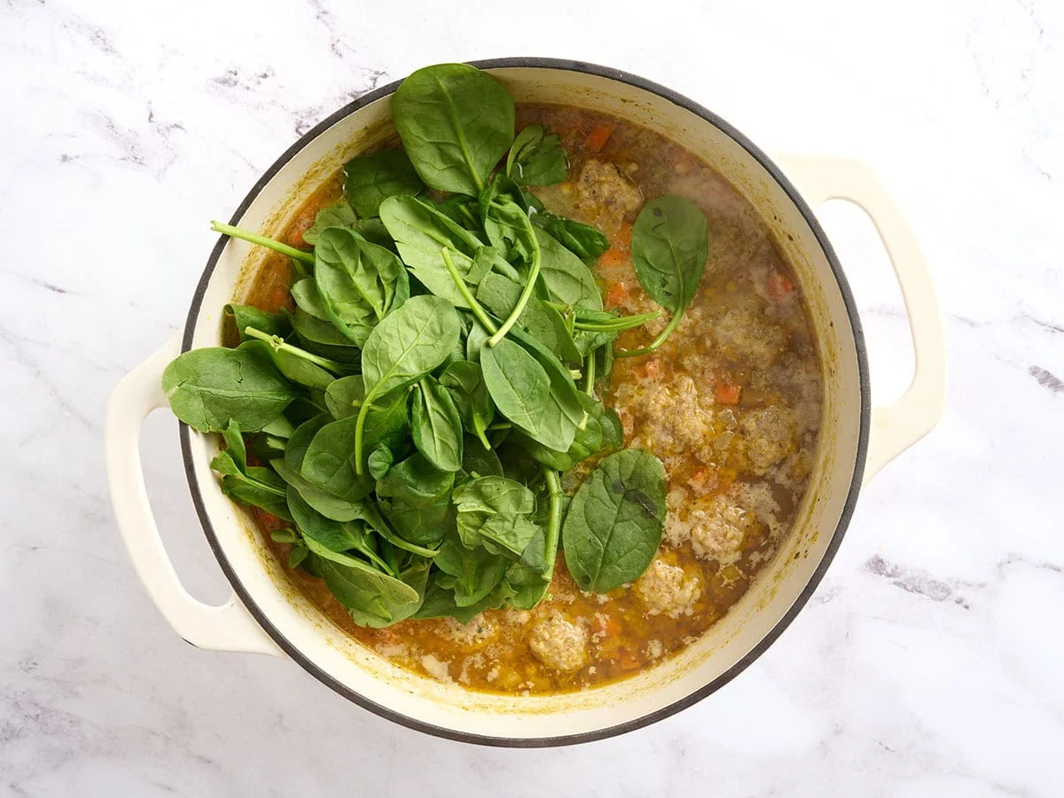 Spinach added to a pot of Italian wedding soup