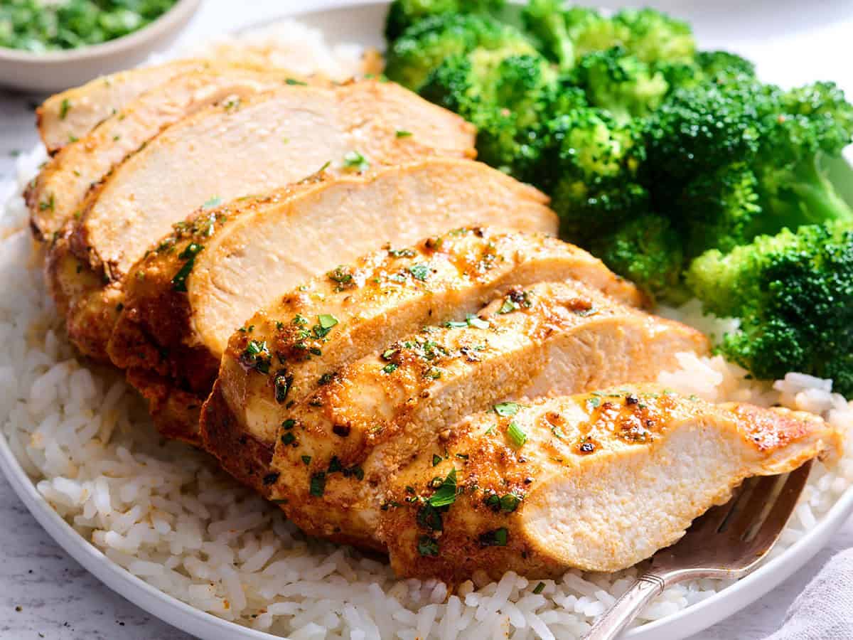 Side view of a baked chicken breast on rice with broccoli.