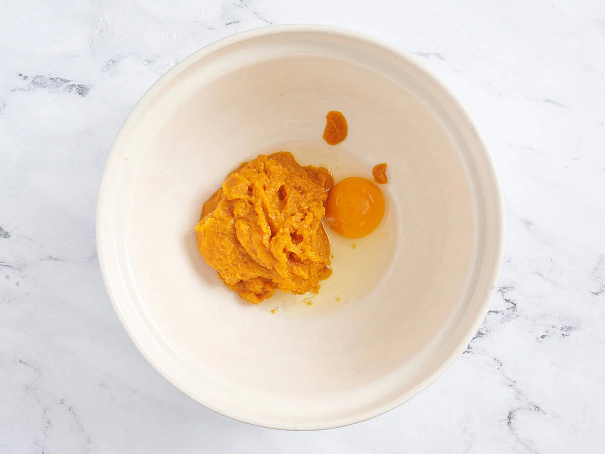 Pumpkin puree and an egg in a mixing bowl.
