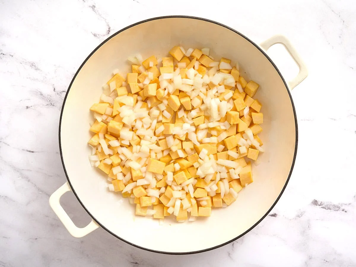 Onion and diced pumpkin in a pot before being sauteed.