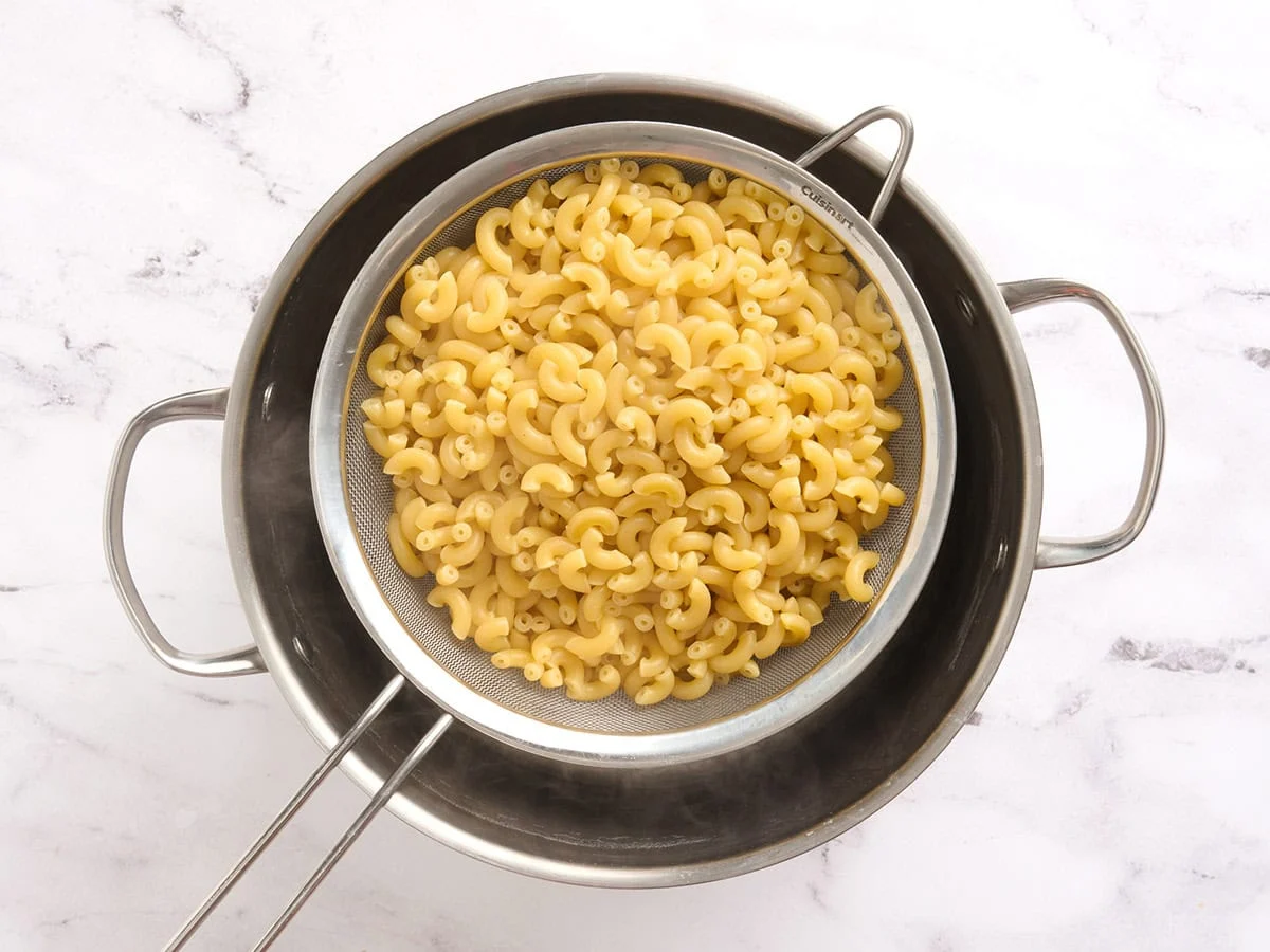 Parboiled macaroni in a strainer.