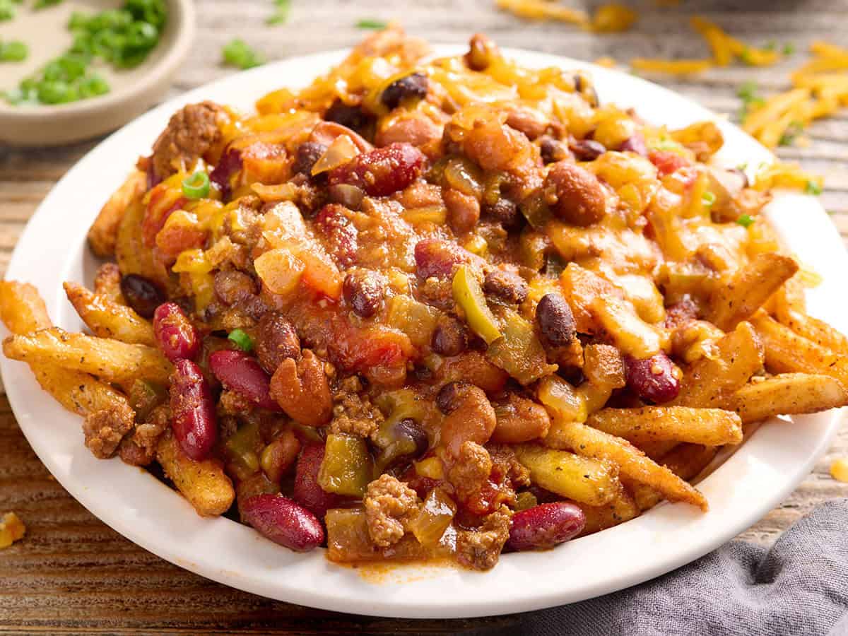 Side view of crockpot chili on a plate of fries.