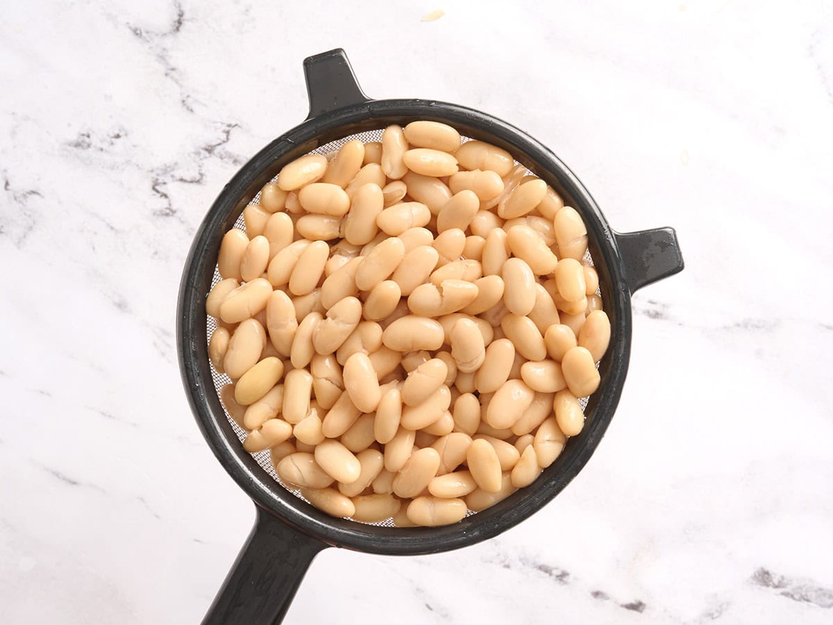Canned white beans in a strainer.