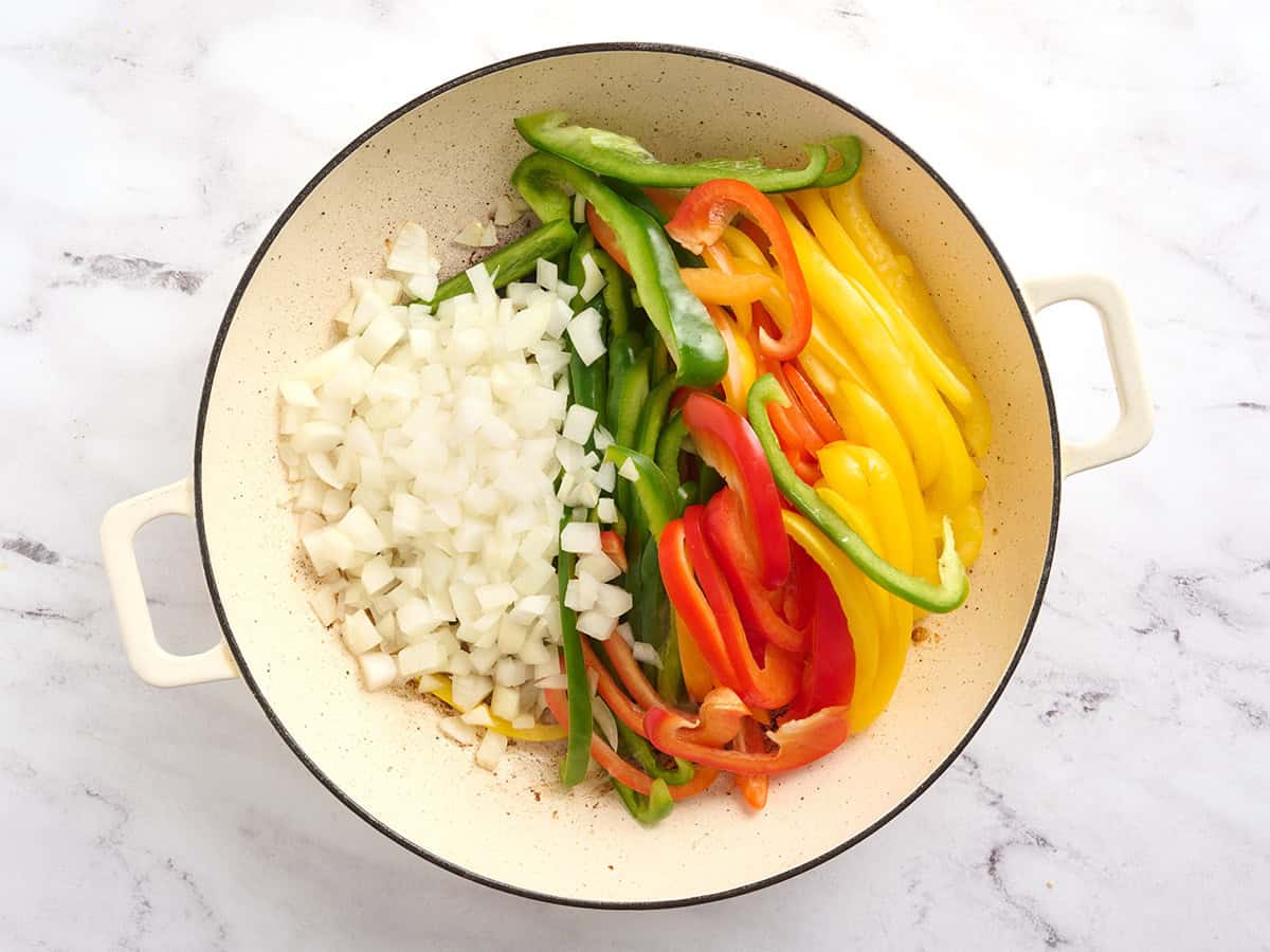 Diced onion and sliced bell peppers in a skillet.