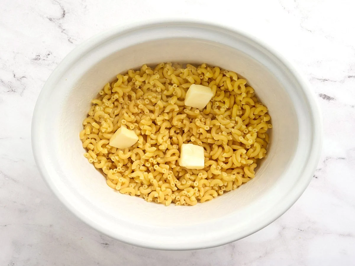 Butter added to par-cooked macaroni in a crockpot.