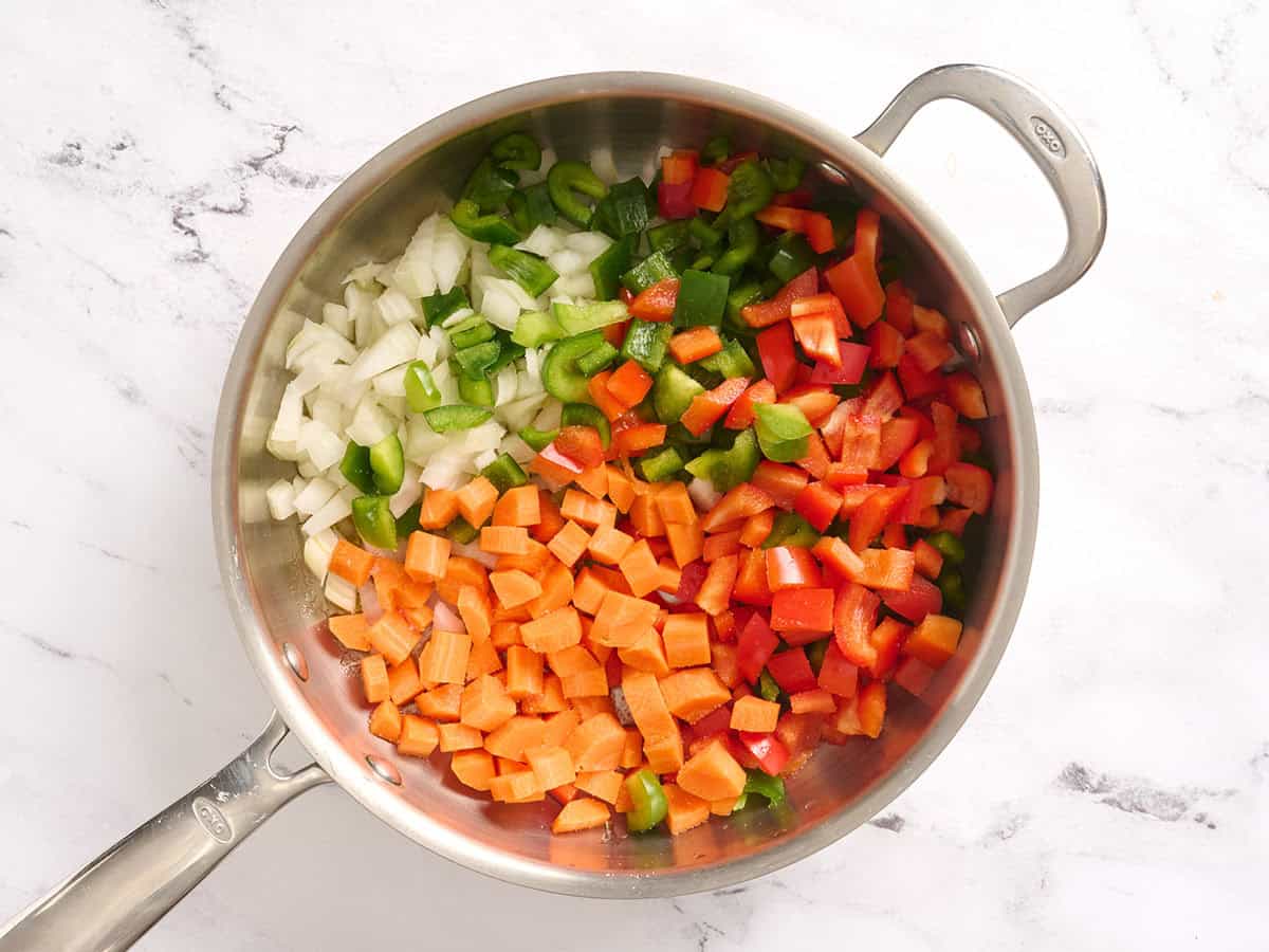 Olive oil, diced carrots, and bell peppers in a skillet.