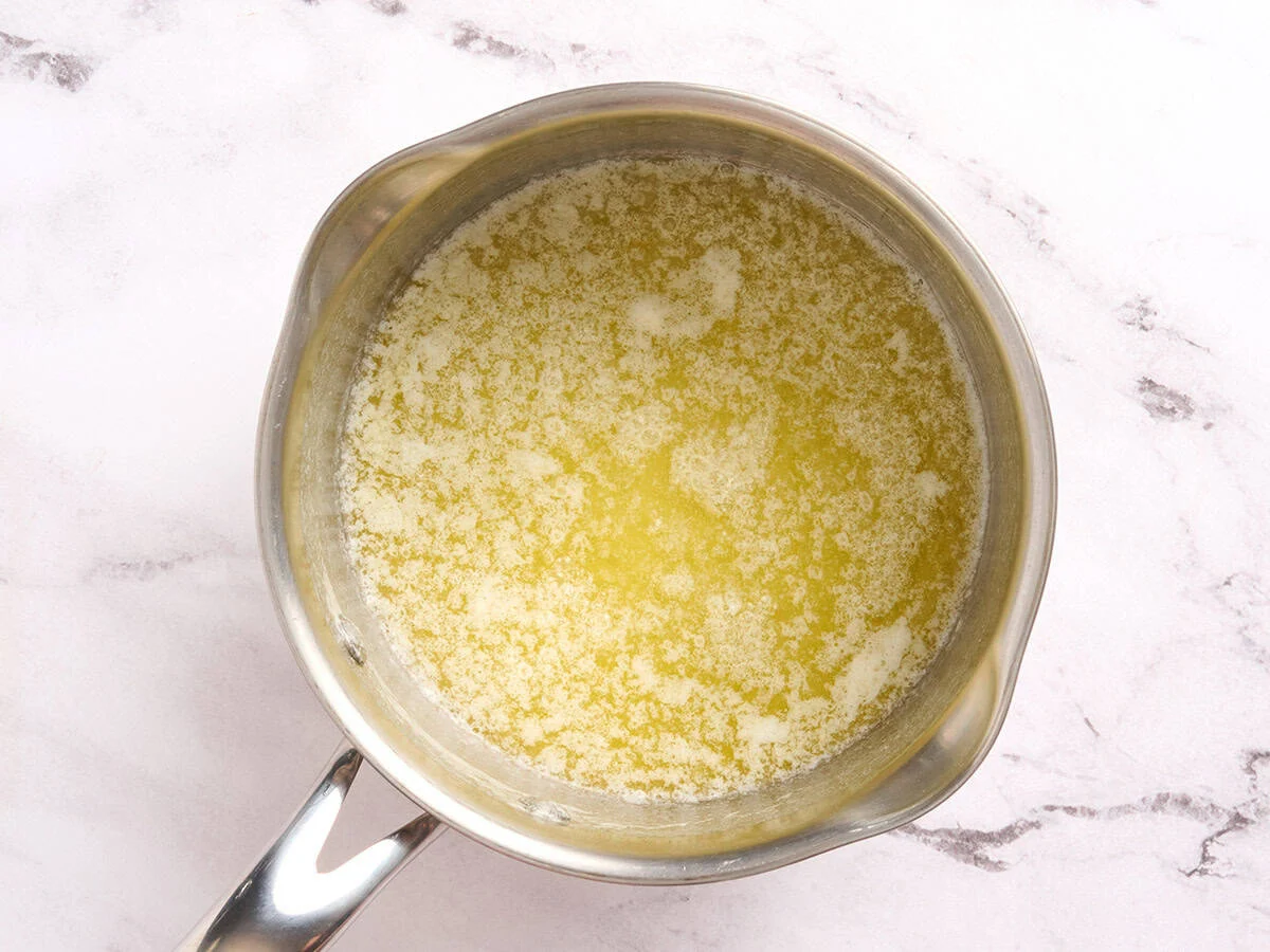 Melted butter in a saucepan halfway through browning.