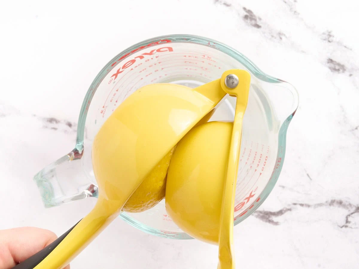 A lemon being squeezed by a juicer.