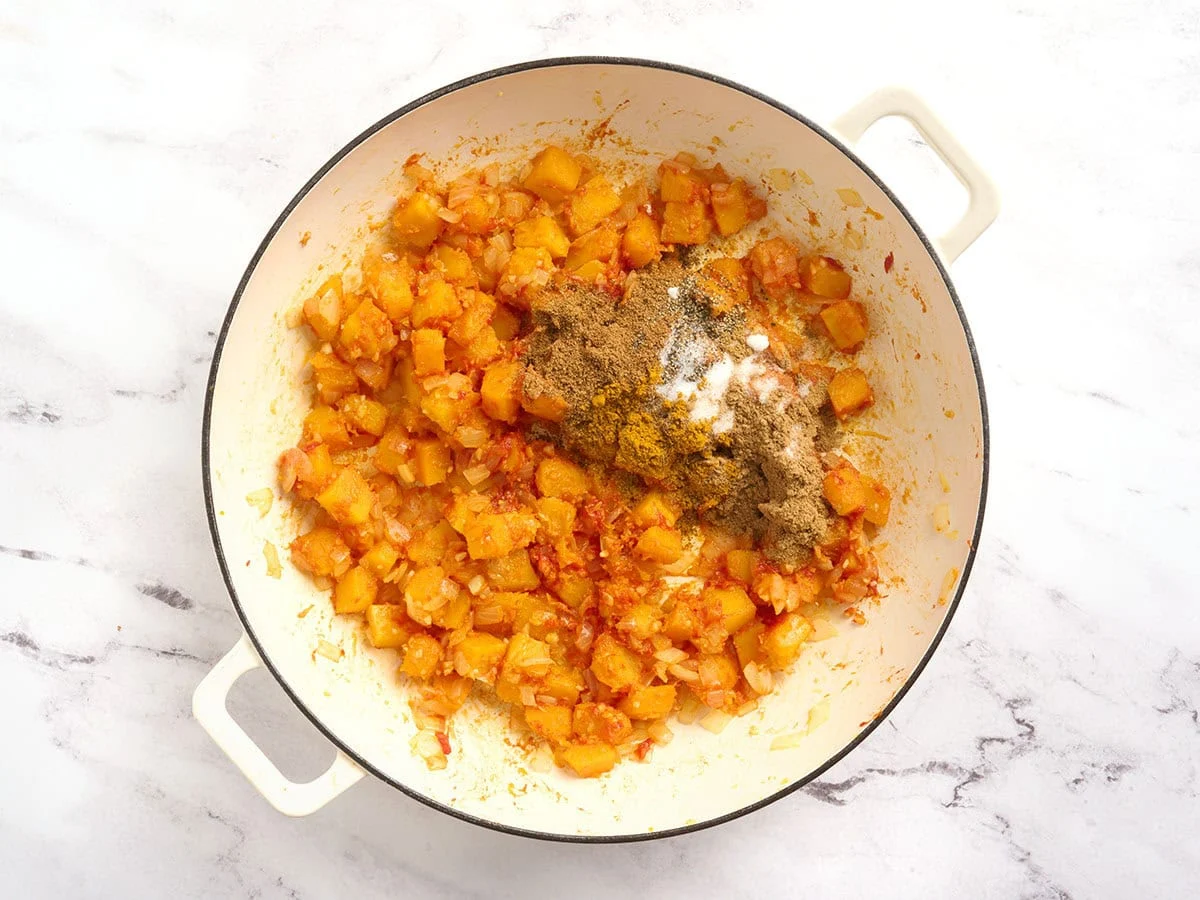 Spiced added to diced pumpkin in a pot.