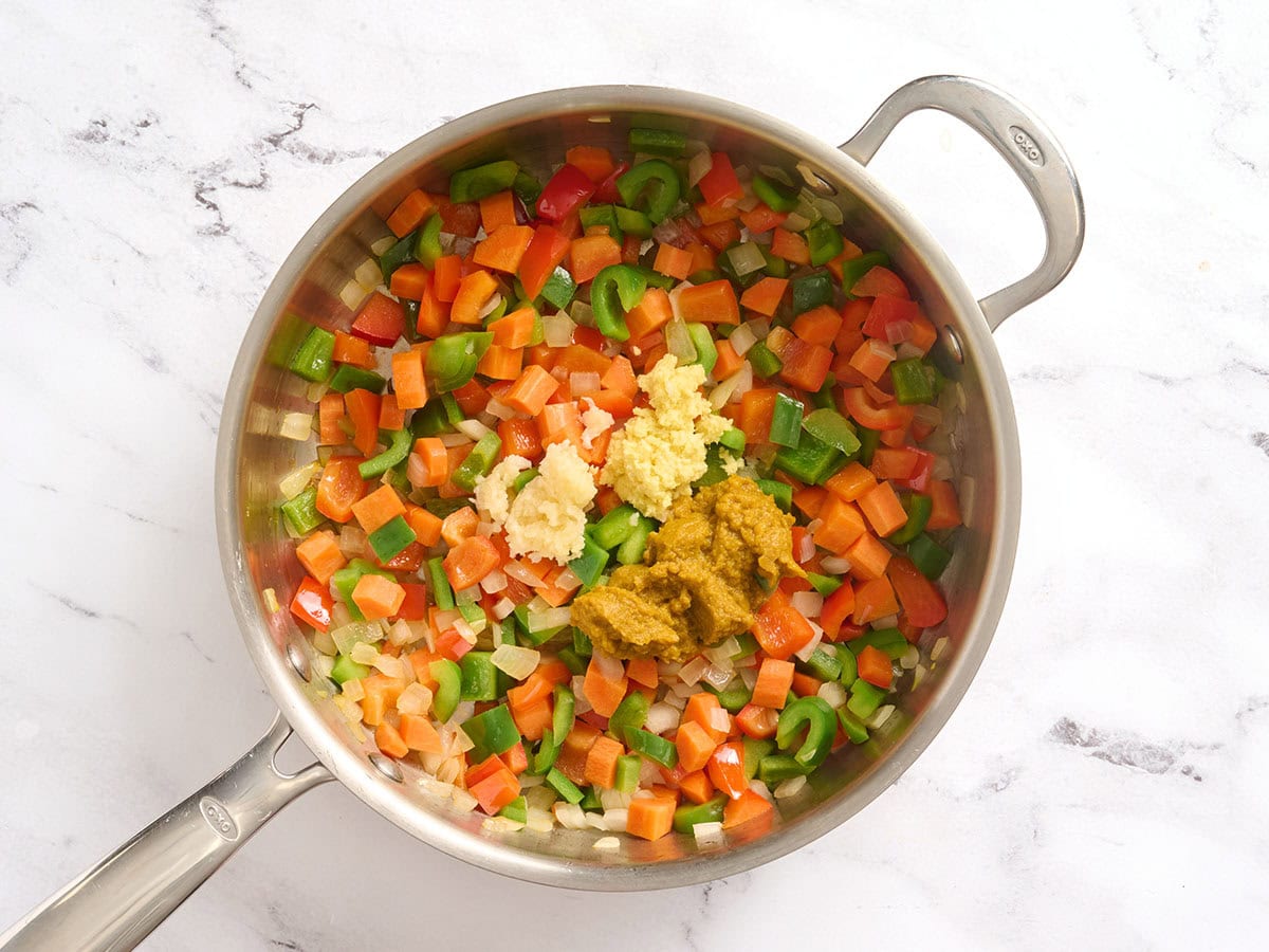 Ginger, garlic and curry paste added to a skillet with sauteed veggies.