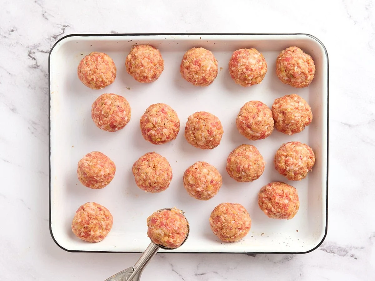 Formed meatballs on a baking sheet.