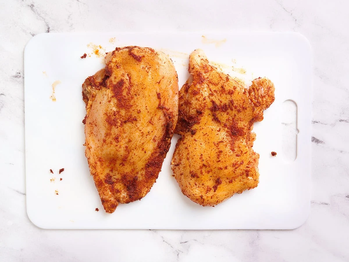Two chicken breasts coated in seasoning.