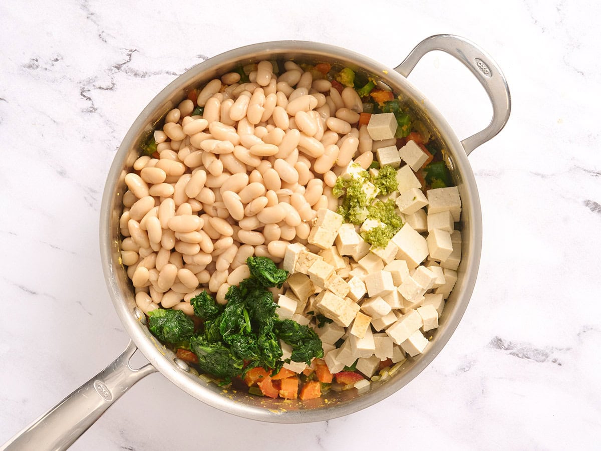 White beans, diced tofu, and lime zest added to a skillet of sauteed veggies.
