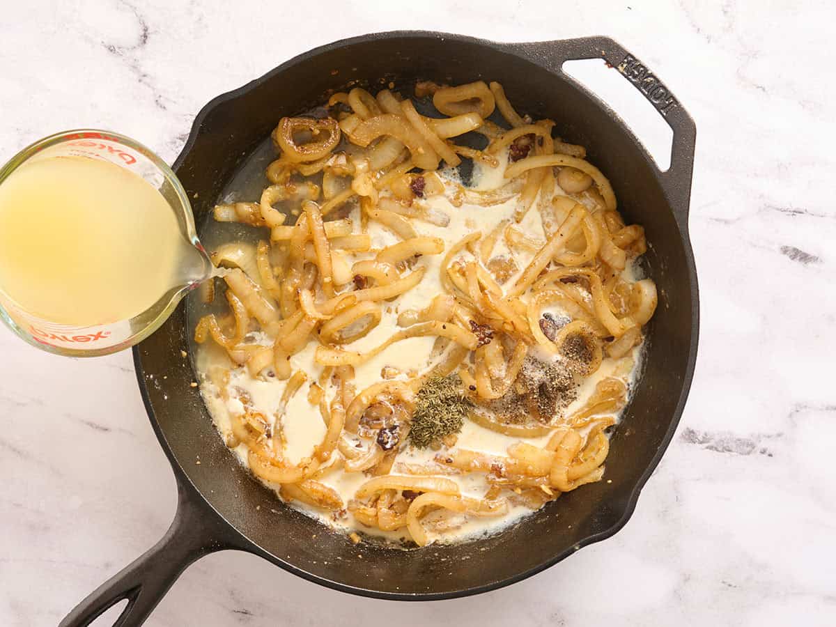 Broth being poured into a skillet with onions, cream and seasonings.