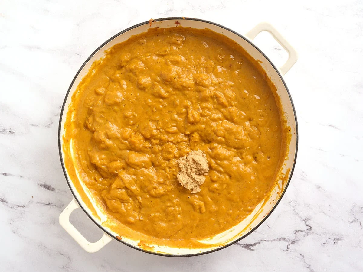 Brown sugar added to a pot of pumpkin curry.