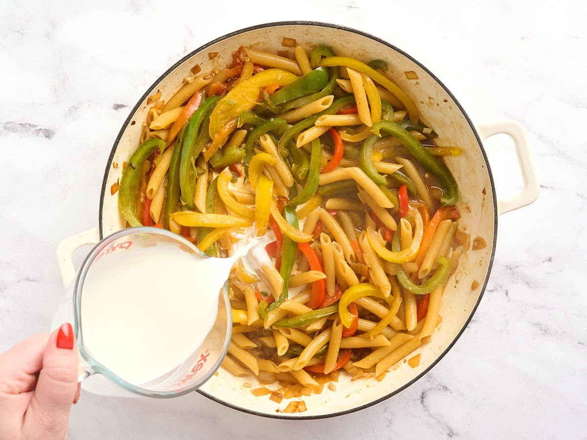 Half and half being poured into a pot of rasta pasta.